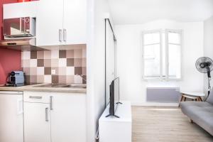 uma cozinha com armários brancos e uma televisão num balcão em Appartement 3 - tout équipé - Carmes, Toulouse em Toulouse