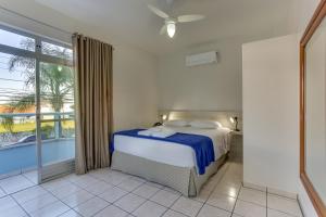 um quarto com uma cama e uma grande janela em Marazul Apart Hotel em Florianópolis