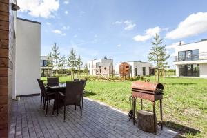 a patio with a table and chairs and a grill at Holiday House Palanga with Hot Tub in Palanga