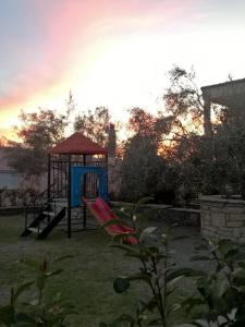 um parque infantil com um baloiço num quintal em Antonia's Apartments em Yimnón