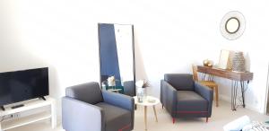 sala de estar con 2 sillas y TV en Le Particulier - Appart Hotel, en La Réole