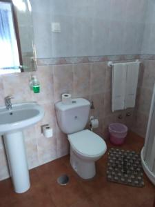 a bathroom with a white toilet and a sink at Quartos Abelha in Porto Covo