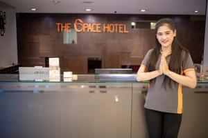 Una mujer parada frente a un mostrador con las manos al frente en The Space Hotel SHA Plus en Chiang Rai