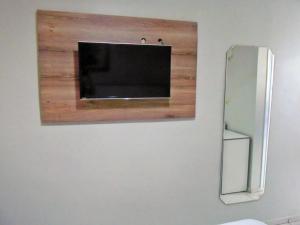 uma televisão de ecrã plano numa parede ao lado de um frigorífico em Titão Plaza Hotel em Campina Grande