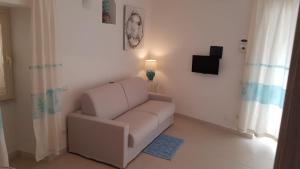 a living room with a white chair and a television at Monolocale II La Maddalena in La Maddalena