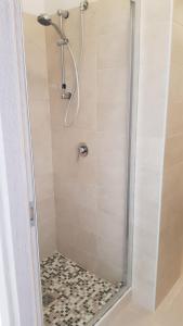 ducha con puerta de cristal y suelo de baldosa en Monolocale II La Maddalena en La Maddalena
