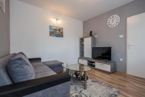 a living room with a couch and a tv at Apartman Adriatic in Ka&scaron;tela