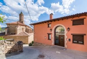 an orange building with a door and a church at El Castillo de Celia in Cubla
