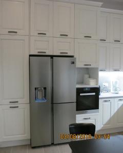 a kitchen with a stainless steel refrigerator and white cabinets at Andoni's House in Pitrofós