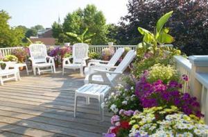 a group of white chairs sitting on a deck with flowers at Yankee Peddler Inn in Newport