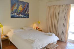 een slaapkamer met een wit bed en een schilderij aan de muur bij TP Aqua Marina, Vilamoura Triplex Apartment in Quarteira