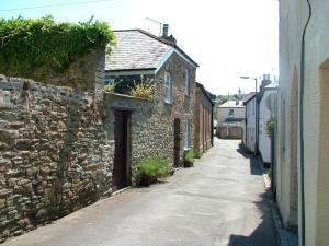 ロストウィジエイにあるGeranium Cottage, Lostwithielの通路横の古い石造りの建物のある路地