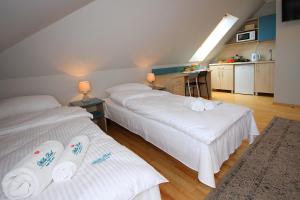 two beds in a room with white sheets at Apartamenty Dorotowo in Dorotowo