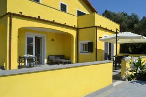 une maison jaune avec une terrasse et un parasol dans l'établissement A Casa Mia, à Levanto