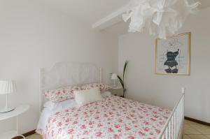 una camera bianca con un letto con fiori rosa di Casa Marisa a Sirmione