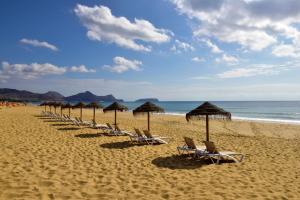 a row of chairs and umbrellas on a beach at Pestana Colombos Premium Club - All Inclusive in Porto Santo