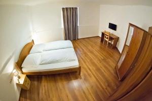 1 dormitorio con 1 cama y suelo de madera en Vadszőlő Vendégház, en Veszprém