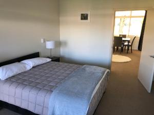 a bedroom with a bed and a dining room at Waitaki Lakes Apartments - Otematata in Otematata