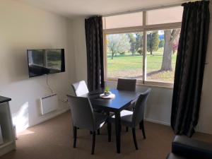 a dining room with a table and chairs and a window at Waitaki Lakes Apartments - Otematata in Otematata