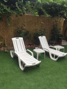 three white lounge chairs and a table on the grass at Alojamiento Turístico Las Catonas de Antoñanzas in Rincón de Soto