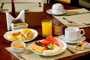 a table with plates of food and a cup of orange juice at Beach Class Convention By Mai in Recife