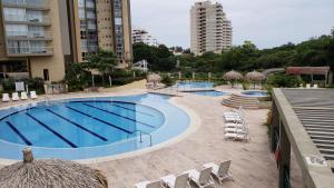 uma piscina com cadeiras e guarda-sóis ao lado de um edifício em Apartamento Santa Marta - Zazue - Bello Horizonte em Santa Marta