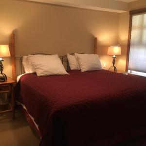 Schlafzimmer mit einem Bett mit roter Bettwäsche und weißen Kissen in der Unterkunft Taynton Lodge at Panorama Mountain Village Resort in Panorama