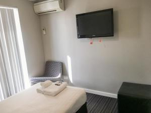 a room with a bed and a tv on the wall at The Premier Hotel Broadmeadow in Newcastle