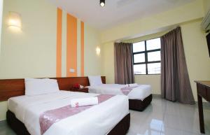 a hotel room with two beds and a window at Sun Inns Hotel Sitiawan in Sitiawan