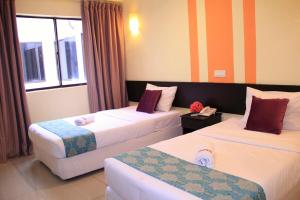 een hotelkamer met 2 bedden en een raam bij Sun Inns Hotel Sitiawan in Sitiawan