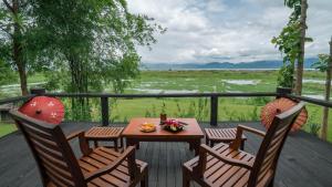 a table and chairs on a deck with a view of a field at Villa Inle Boutique Resort in Nyaungshwe Township