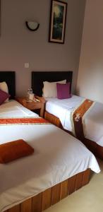 a bedroom with two beds with white and purple pillows at Apex Koh Kong Hotel in Koh Kong
