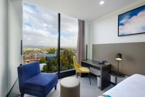 a room with a bed, chair, desk and a television at Mantra Albury in Albury