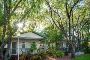 people standing on the porch of a house with trees at Mandalay Holiday Resort and Tourist Park in Busselton