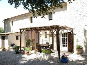 a wooden pergola in front of a house at Cottages de Garrigue in Fonroque