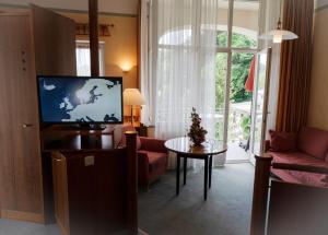 a living room with a flat screen tv and a table at Hotel Erika in Bad Reichenhall