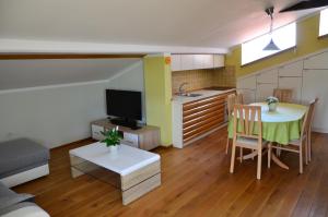 pequeña sala de estar con mesa y cocina en Apartma Louis, en Dutovlje