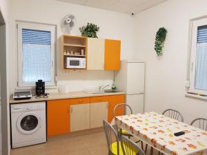 ソンバトヘイにあるSzatmárházのキッチン(オレンジ色のキャビネット、テーブル、電子レンジ付)