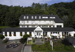 un grand bâtiment blanc avec des motos garées devant lui dans l'établissement Luckai Hotel & Restaurant Inhaber Dennis Burmann, à Freienohl