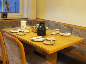 einem Holztisch mit Tellern und Tassen und einer Vase darauf in der Unterkunft Darmstädter Hof in Mainz