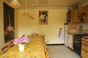 - une cuisine avec une grande table ornée de fleurs roses dans l'établissement Kerbave Braz, à Plouzélambre