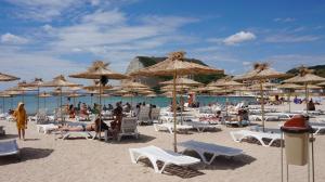 a beach with chairs and umbrellas and people on the sand at Stefy Beach Apartment in Kavarna