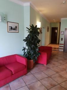 a living room with two red couches and a potted plant at Hotel San Pietro in Assisi