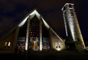 une église avec un bâtiment allumé la nuit dans l'établissement Brasserie Michel / Cesar Hotel, à Le Portel