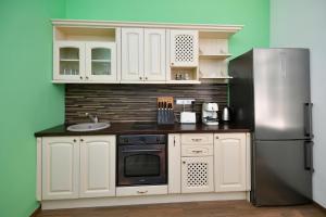 eine Küche mit weißen Schränken und einem Kühlschrank aus Edelstahl in der Unterkunft Apartament Shipka 2 in Warna