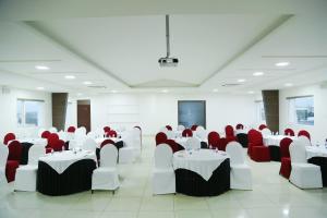 a banquet hall with white tables and red chairs at Hotel Jump In & Out in Coimbatore