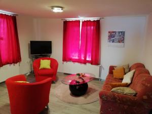 a living room with red furniture and pink curtains at Haus Bruni in Graftlage