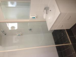 a bathroom with a shower with a sink and a mirror at Budget Motel in Midland Junction