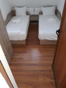 two beds in a room with wooden floors at Апартаменти Прометей in Burgas