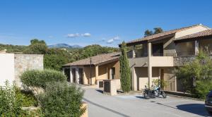 une moto garée devant un bâtiment dans l'établissement Résidence Odalys Les Hameaux de Capra Scorsa, à Belgodère